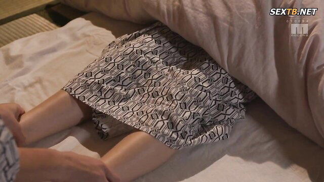 Julia under sheets in kimono skirt, legs spread, hands caressing thighs in JAV scene