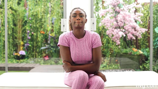 Confident black girl in pink tracksuit sits smiling confidently