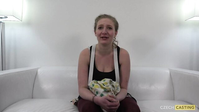 Young mom at Czech casting sits nervously on couch in tank top and suspenders