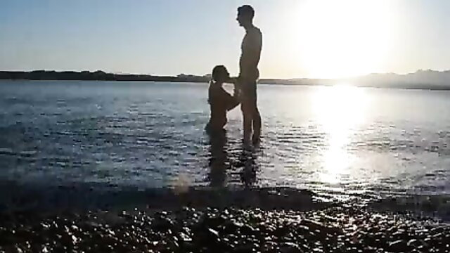 Silhouette couple nude in shallow water at sunset, risky outdoor fuck