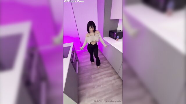 Asian teen in off-shoulder top and pants dances seductively in kitchen