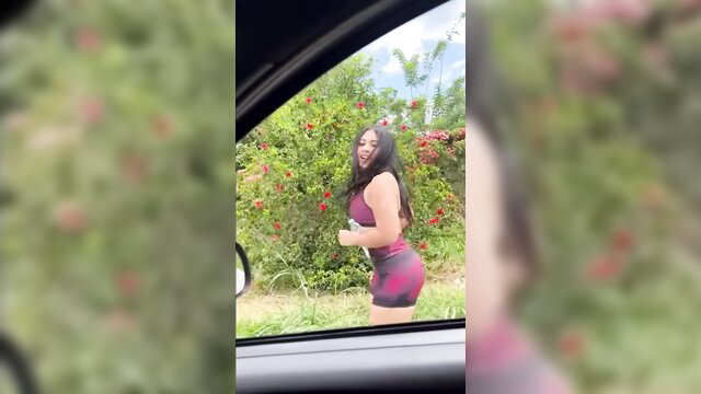 Hot Latina in tight maroon shorts dances by car, big ass tease