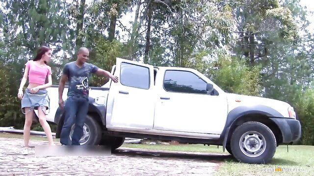 Blonde Colombian waitress in pink skirt stands by pickup truck with black guy