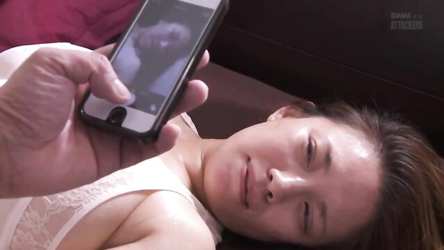 Asian wife in lingerie holds phone with man's dick pic, seductive bedroom gaze