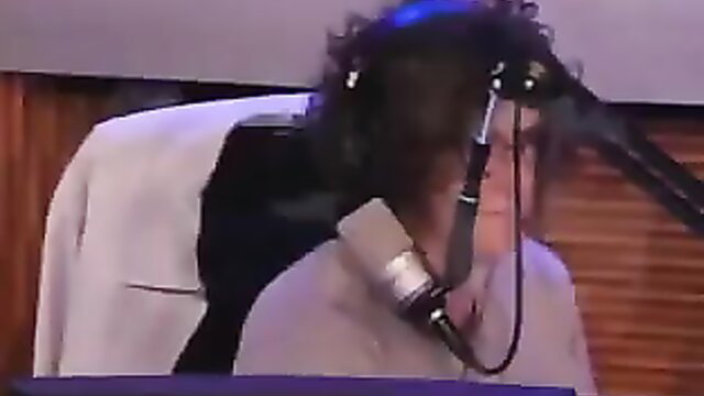 Sarah on Stump The Booey mic stage, curly hair, gray jacket, closeup