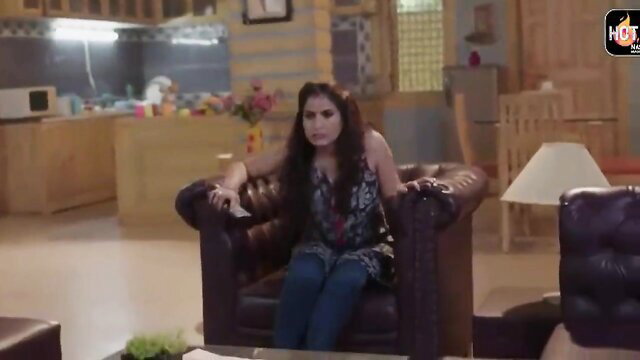 Desi Indian wife in tank top and jeans sits seductively on chair