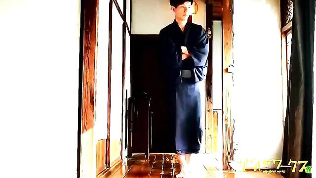Fit Asian man in navy kimono stands arms crossed in JAV gay scene