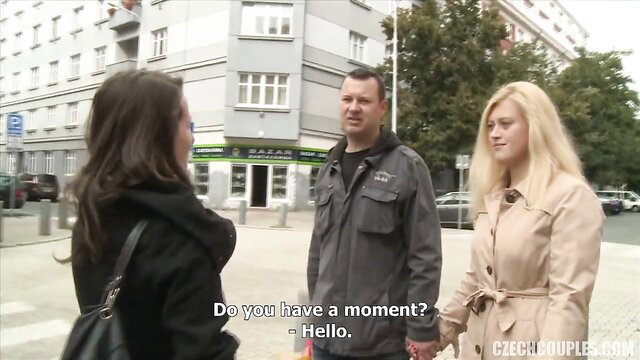 Three Czech swingers outdoors: brunette, man, blonde in coats chatting