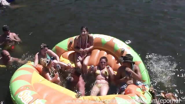Hot spring break teens crowd massive inflatable float in skimpy bikinis