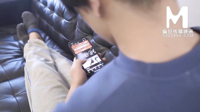 Man lounging on couch scrolls phone, horny friend shelter scene