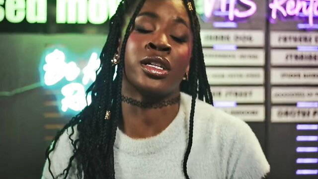 Black beauty with braids smirks seductively in neon-lit club, glossy lips parted