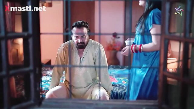 Indian couple in traditional attire, man sitting, woman in blue dress standing