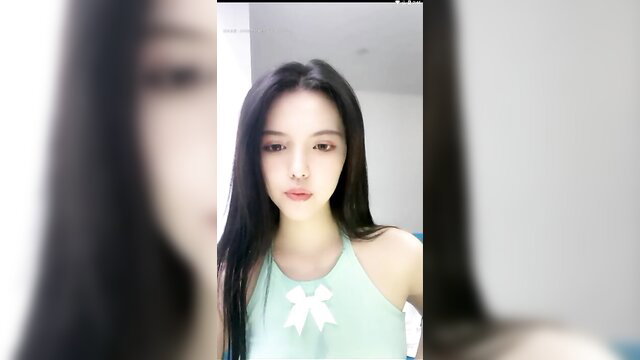 Asian beauty in green bow top, long black hair, seductive gaze