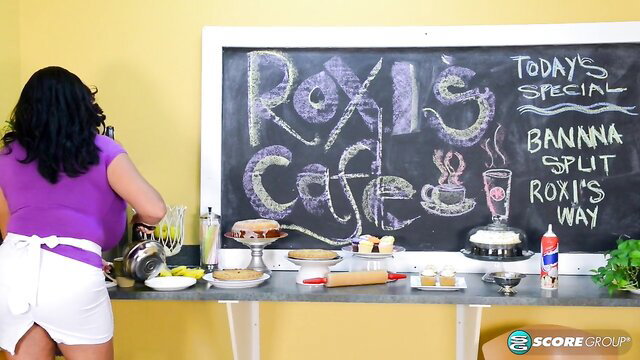 Roxi Red in tight apron at cafe, big tits brunette bending over counter