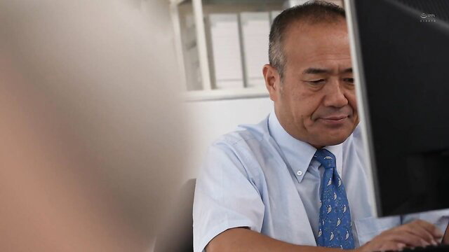 Shiori Tsukada with older man at desk in JAV office scene