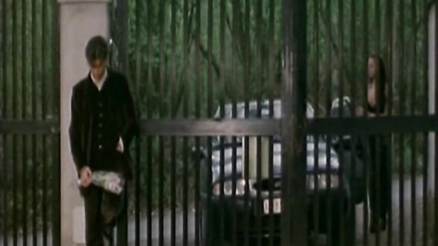 Julia Channel in La Reporter E Il Sesso at black gate with man, sexy dress