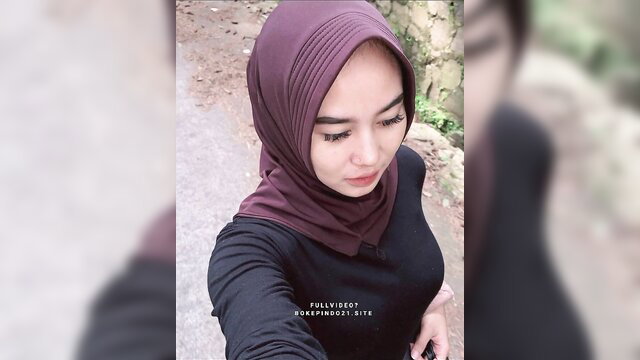 Indonesian hijab babe in tight black top, seductive selfie outdoors