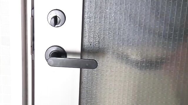 Shiomi Yuriko peeks seductively through frosted glass door with black door handle