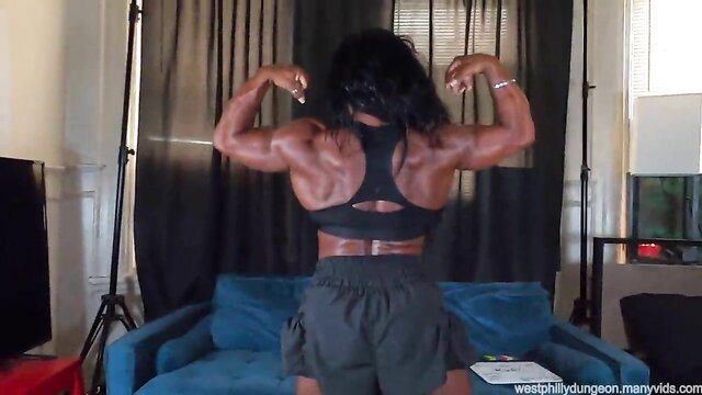 Ruby Muscle flexing ripped back muscles in sports bra and shorts