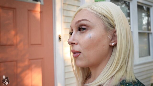 Blonde bombshell Alexis Andrews outside house door, seductive gaze