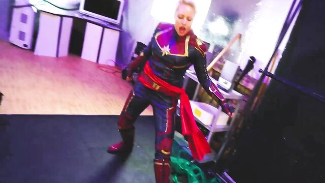 Blonde Captain Marvel cosplay babe in tight latex suit posing sexy
