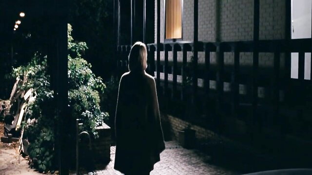 Mystery blonde in dark coat walks to lit window at night, Queen of Hearts tease