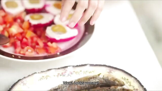 Woman's hand grabs colorful veggie-stuffed eggs and anchovies on plate, looks yummy