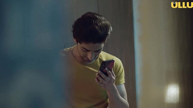 Handsome young Indian man in yellow t-shirt holding phone, Ullu Adha Adhura Pyaar