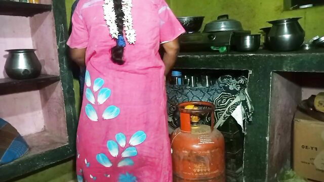 Indian village girl in pink dress at kitchen stove