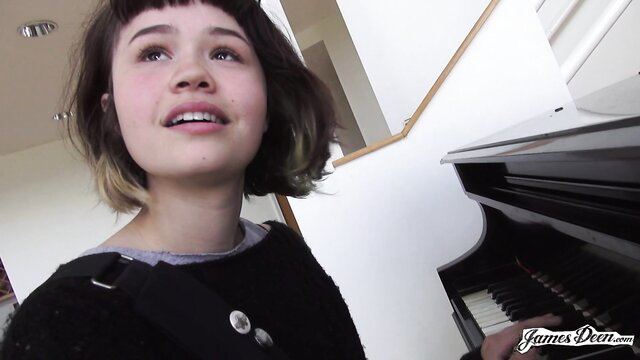 Yhivi smiling at camera by piano in James Deen adult video