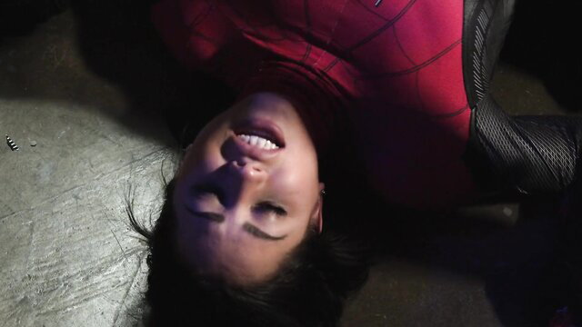 Spider Woman upside down on floor in tight red Spider-Man suit cosplay