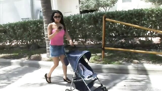 Abella Anderson in pink top and denim skirt pushing stroller outdoors