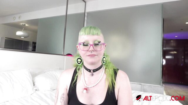Katt Morehead with green hair, choker on bed talks tattoos