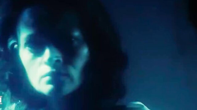 Mysterious brunette with intense gaze in moody blue-lit closeup