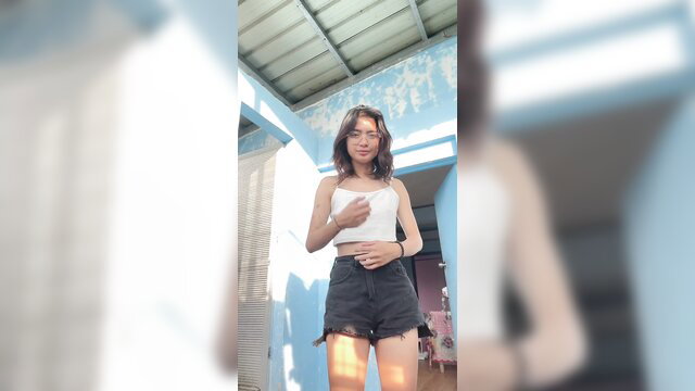 Alt girl in white crop top and ripped denim shorts poses sexy