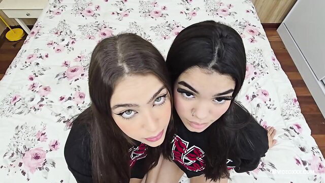 Two sexy brunettes with heavy makeup kissing intimately on bed