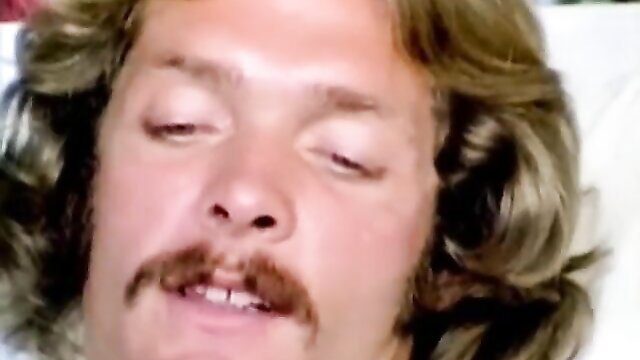 Vintage porn star with long wavy hair and mustache in intense closeup, retro sex ward scene