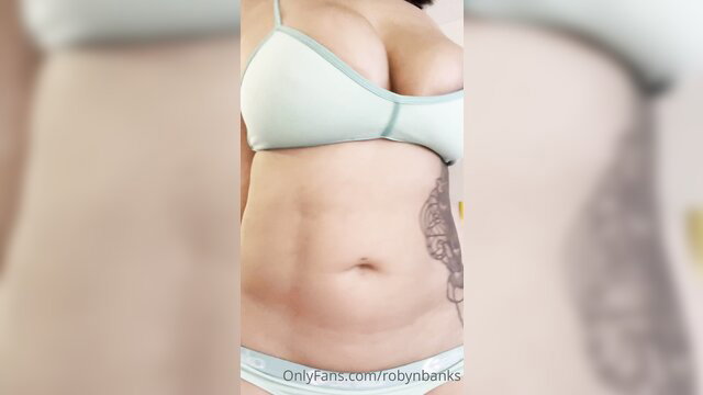 Curvy tattooed brunette in sheer bra showing soft belly and huge tits