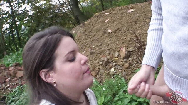 Pretty brunette bitch kneels to suck cock in woods outdoor scene