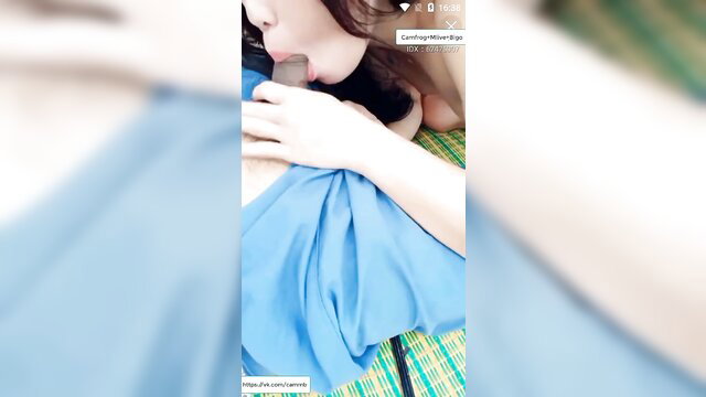 Asian woman in blue dress teases gardener with deep kiss on neck