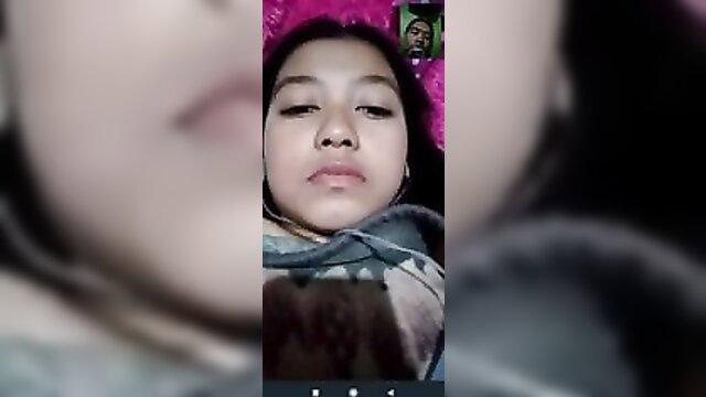Asian teen girl in hoodie on pink bed during video call, lying face-up close-up