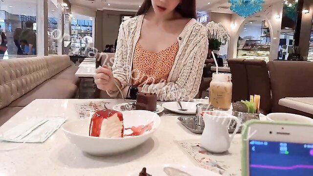 Asian girl in orange dress eating cake at cafe, remote toy orgasm tease