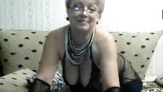 Grey-haired busty granny in sheer black lingerie and gloves smiling seductively