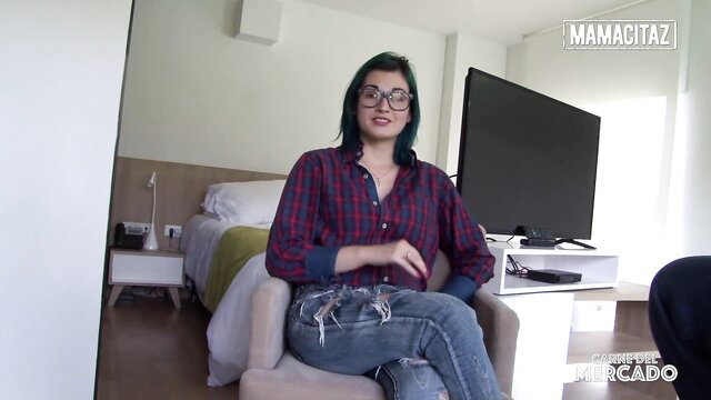 Latina woman sitting in a chair, wearing a plaid shirt and jeans