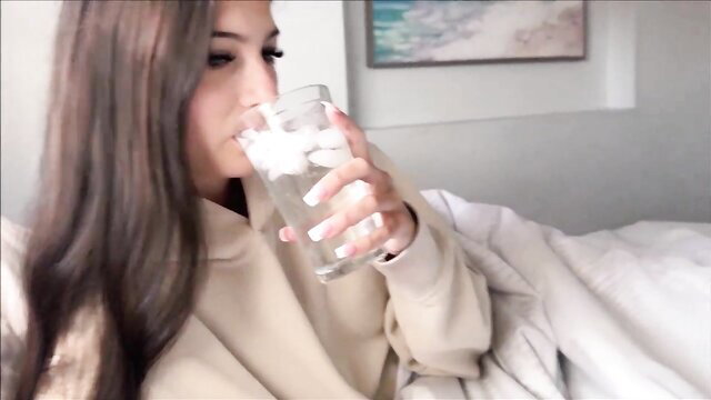 Sophie Tyler sips water in hoodie on bed - Sick Day Step Sis
