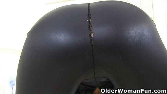 Mature MILF in tight black latex pants showing huge round ass closeup