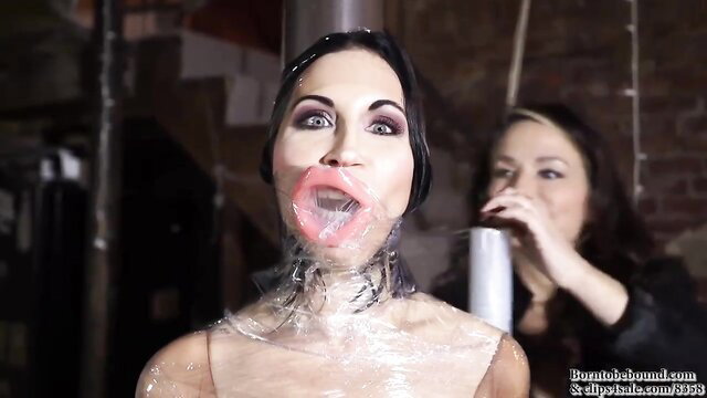 Ball-gagged brunette trussed in plastic wrap, aroused in dungeon