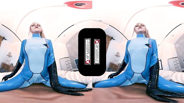 Lila Frey in shiny blue latex Metroid cosplay catsuit, sitting spread legs