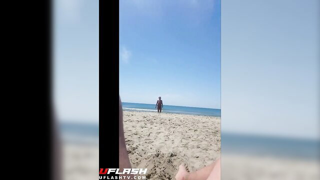Silhouetted man stands nude on sunny beach, teasing outdoor exposure