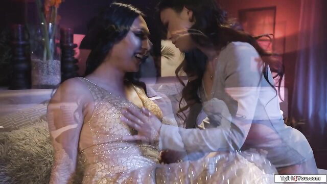 Two sexy Asian trans women kissing intimately in gold dress